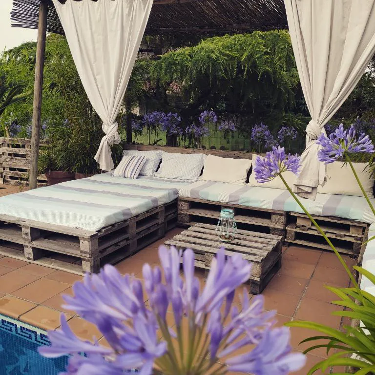 Zona chill-out junto a la piscina con cortinas blancas y cojines, El Atico de Villalmar