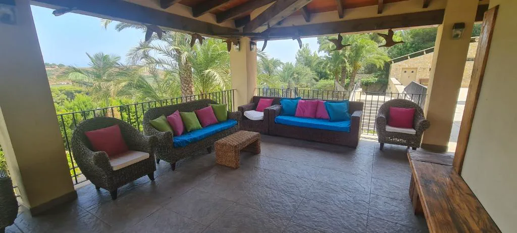 Terraza cubierta con sofás y palmeras al fondo
