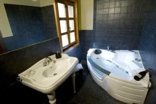 Baño con bañera de hidromasaje esquinera y lavabo blanco