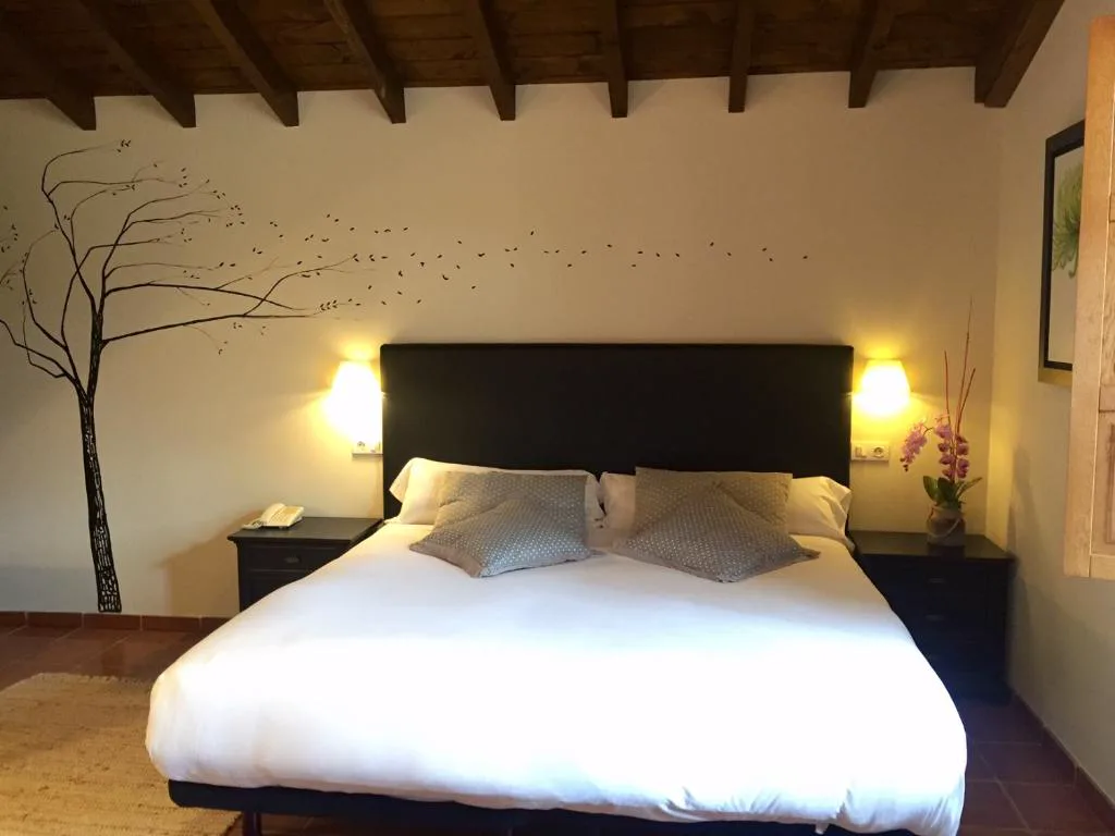 Habitación con cabecero negro y un árbol pintado