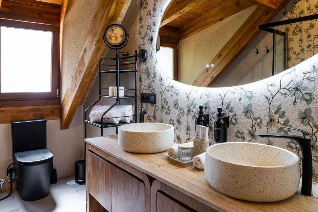 Baño con lavabos de piedra redondos y papel pintado floral