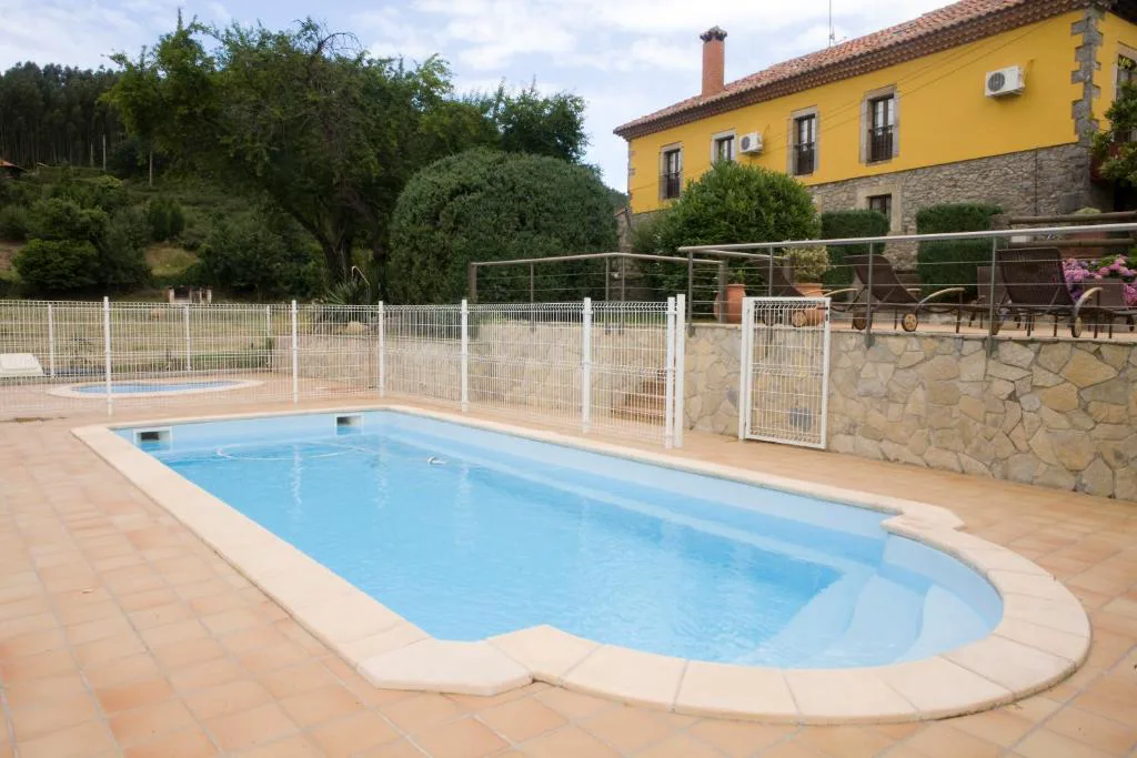 Piscina exterior rodeada de terraza con un edificio amarillo al fondo