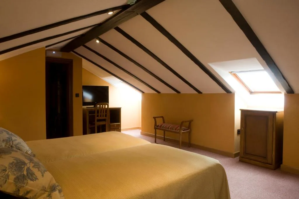 Habitación abuhardillada con vigas de madera y cama doble