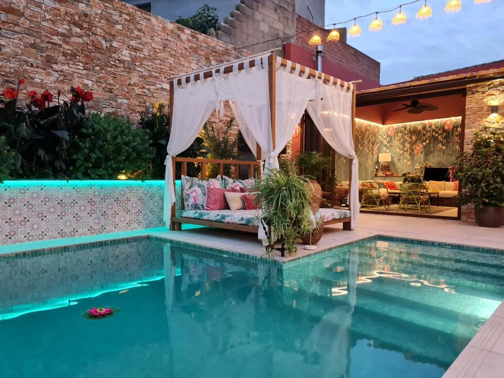 Piscina con cenador de cortinas blancas en el patio