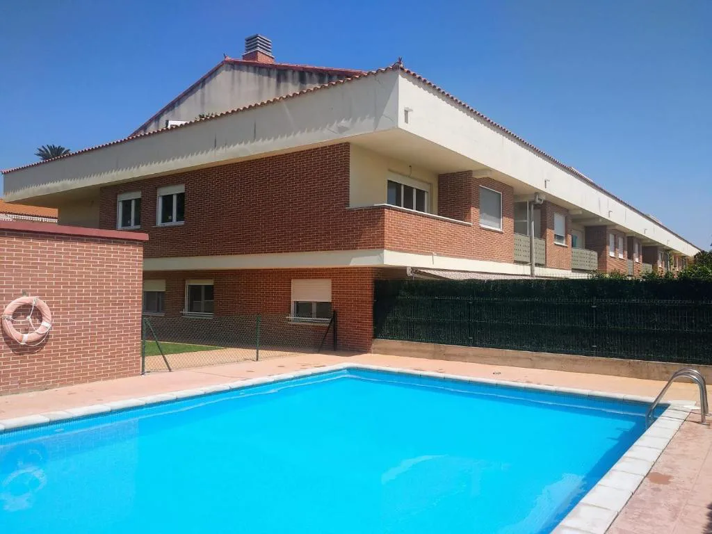 Piscina azul junto a una valla verde y césped