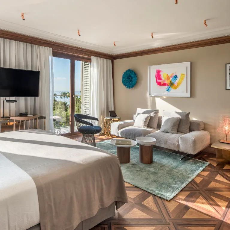 Suite con sofá y arte contemporáneo junto a balcón con vistas al mar, El Llorenç Parc de la Mar
