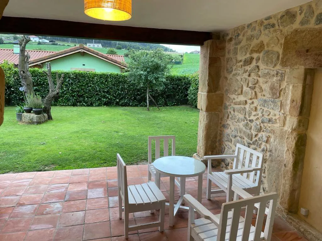 Porche de piedra con mesa y sillas frente al jardín