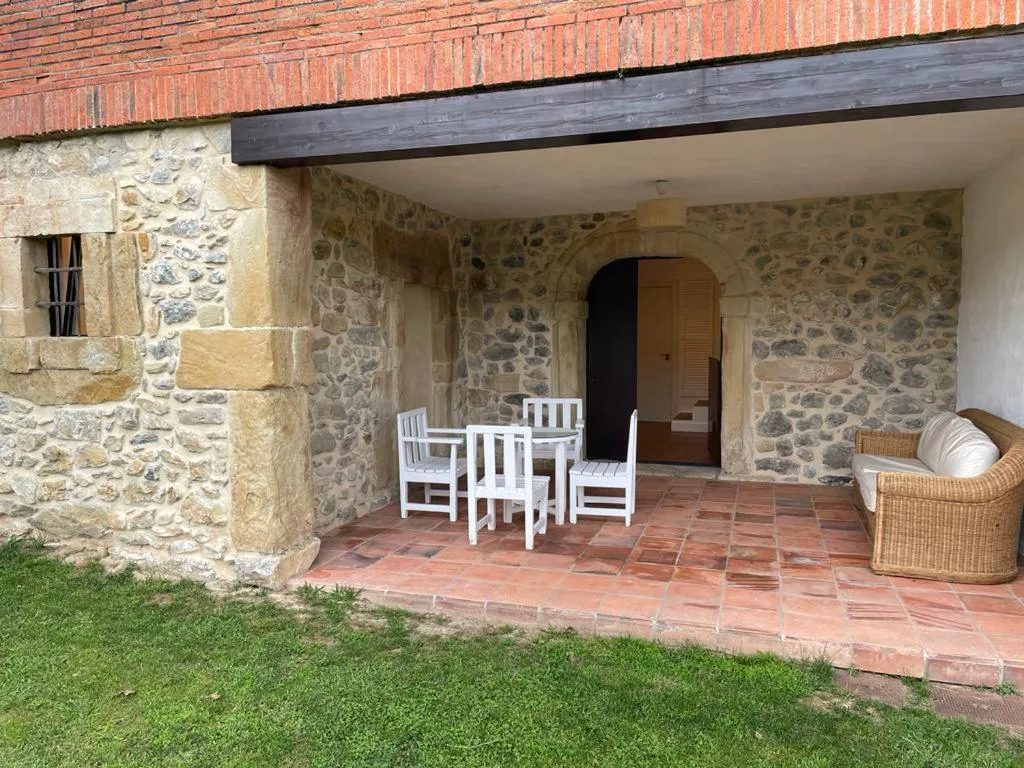 Soportal de piedra con mesa blanca junto al césped