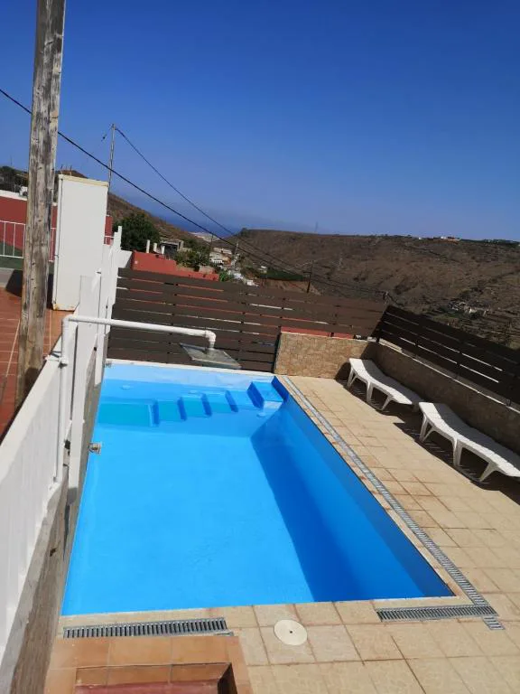 Piscina rectangular junto a una valla de madera oscura con vistas al valle, El Recoveco de La Solana