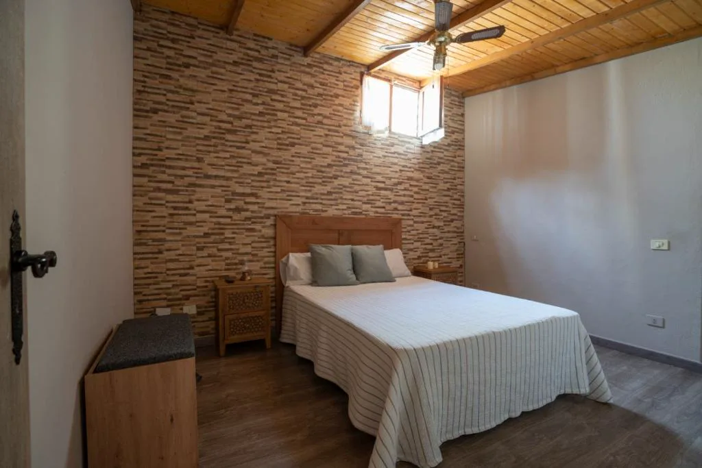 Dormitorio con pared de piedra vista y techo de madera, El Recoveco de La Solana