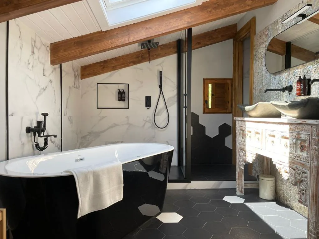 Baño con bañera negra exenta y vigas de madera