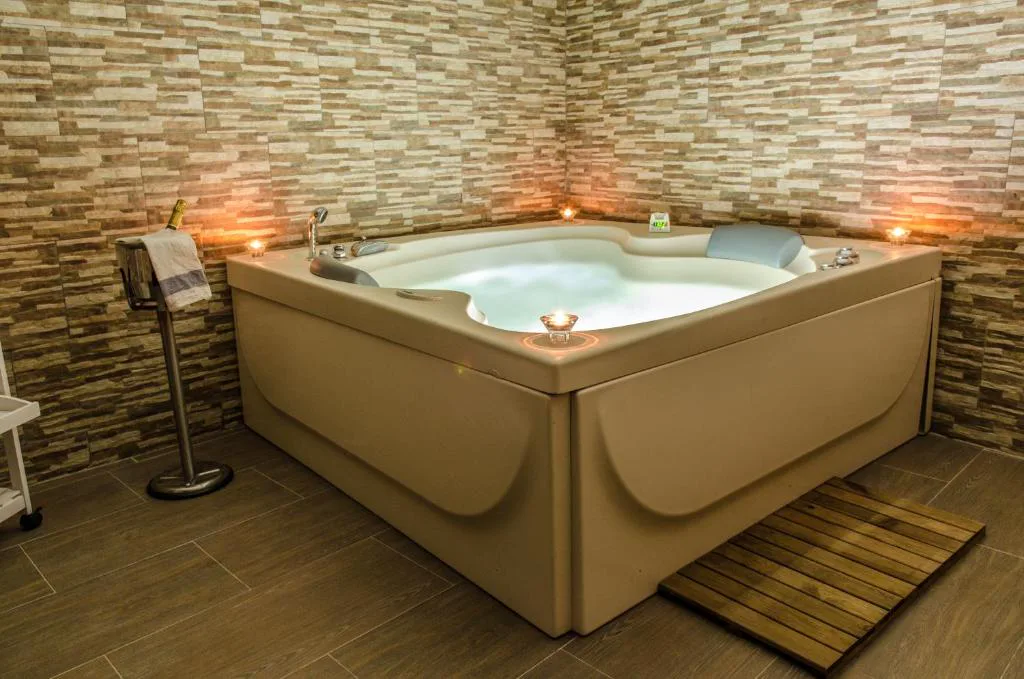 Jacuzzi cuadrado con paredes de piedra y luces cálidas