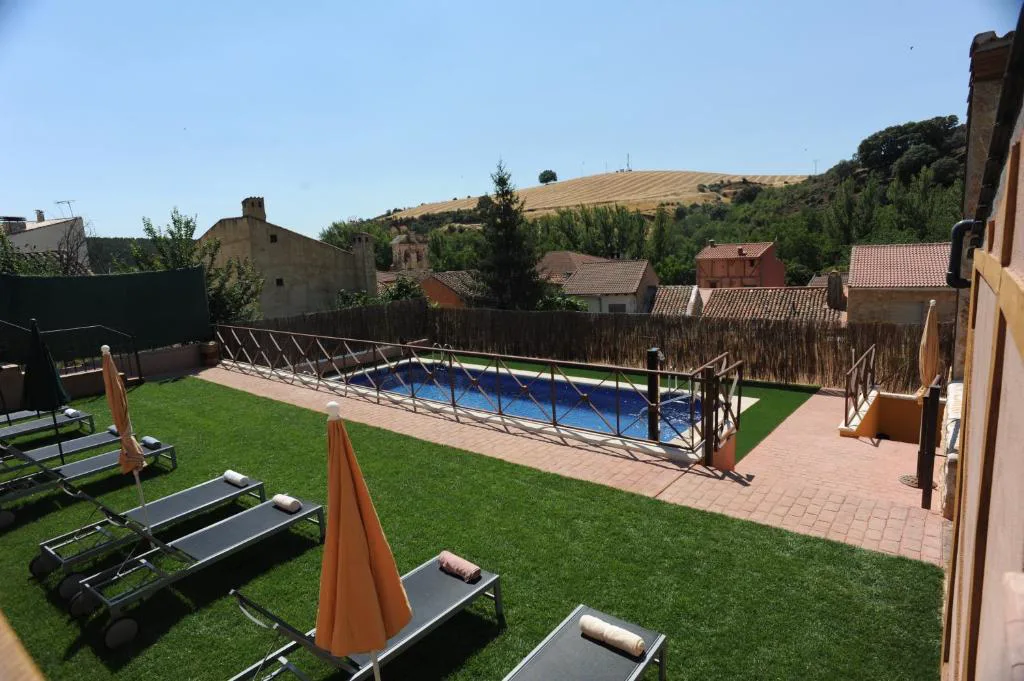 Piscina en un jardín con tumbonas y vistas a las lomas
