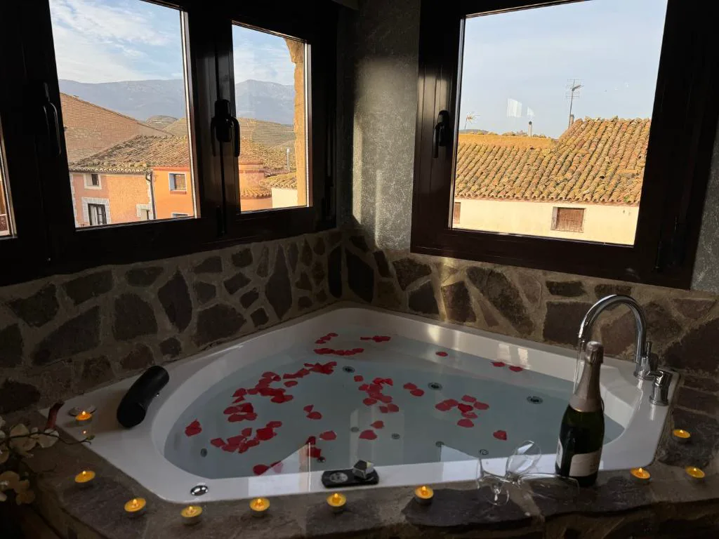 Bañera de hidromasaje con pétalos de rosa junto a una ventana