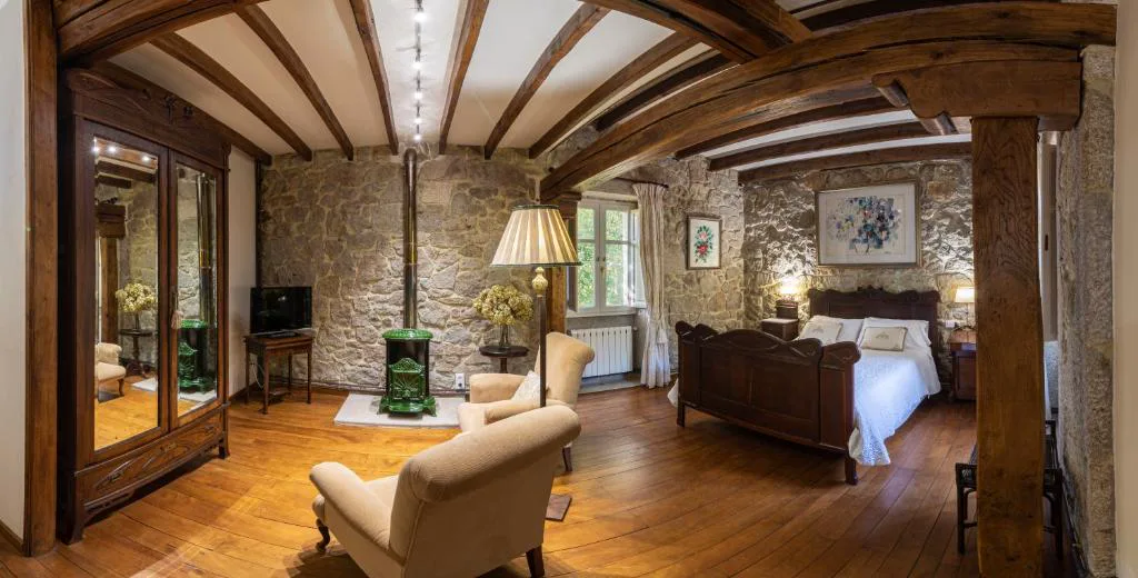 Habitación de piedra vista con estufa de leña verde y sillones de lectura, Entre Os Ríos