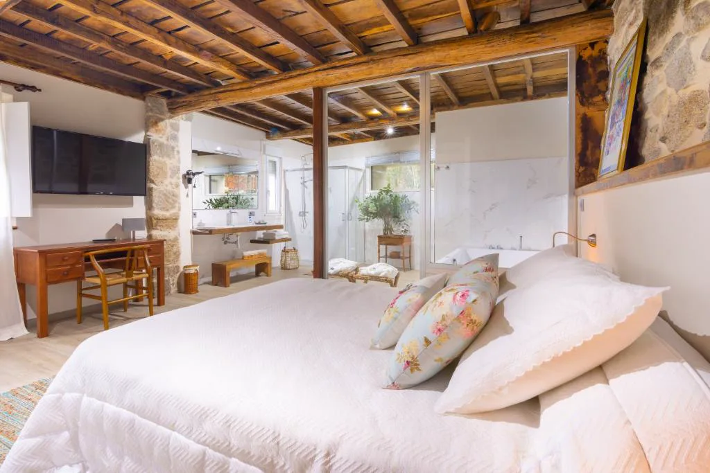 Suite con bañera de hidromasaje integrada tras mampara de cristal junto a la cama, Entre Os Ríos