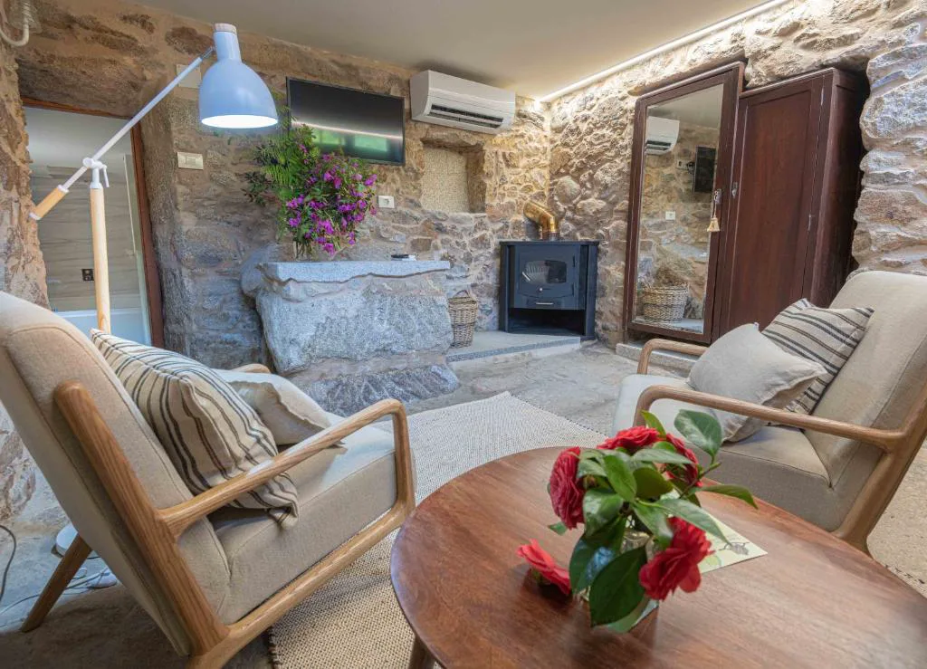 Salón de piedra con chimenea de hierro fundido y ramo de rosas rojas, Entre Os Ríos
