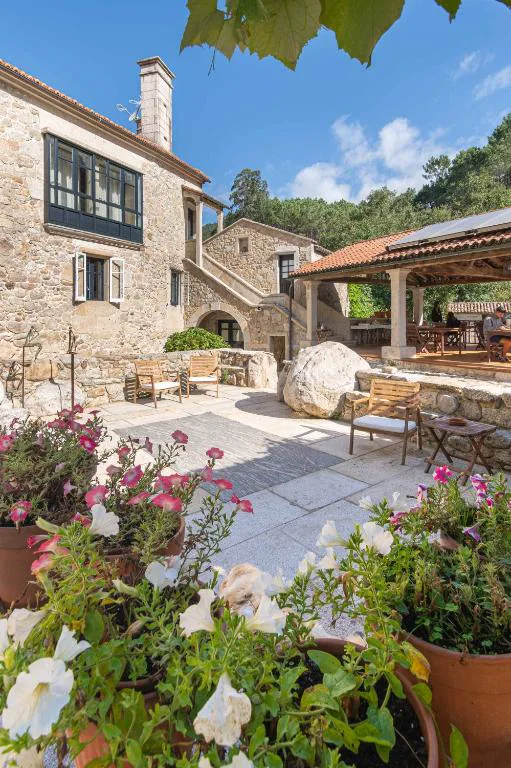 Patio de piedra con pérgola de viña y macetas de flores, Entre Os Ríos