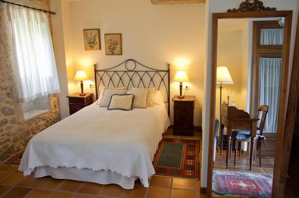 Dormitorio romántico con cabecero de hierro forjado y ropa de cama roja, Entre Os Ríos