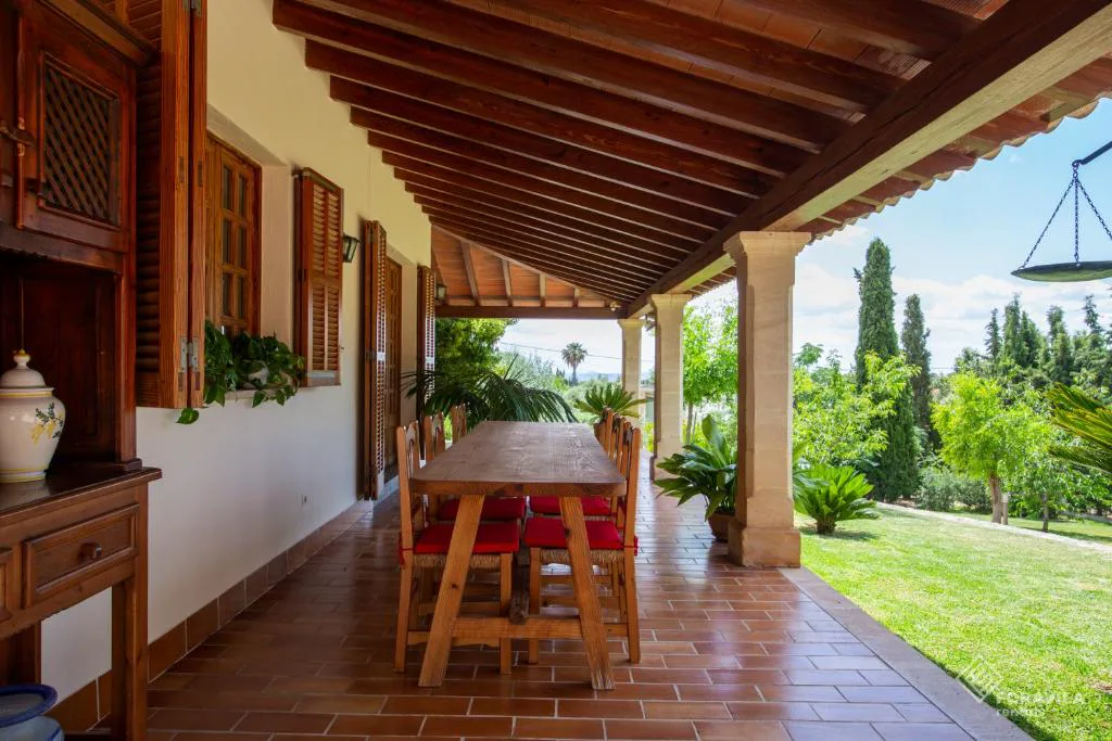 Porche exterior con mesa de madera maciza y vigas vistas, Es Pou de Biniamar