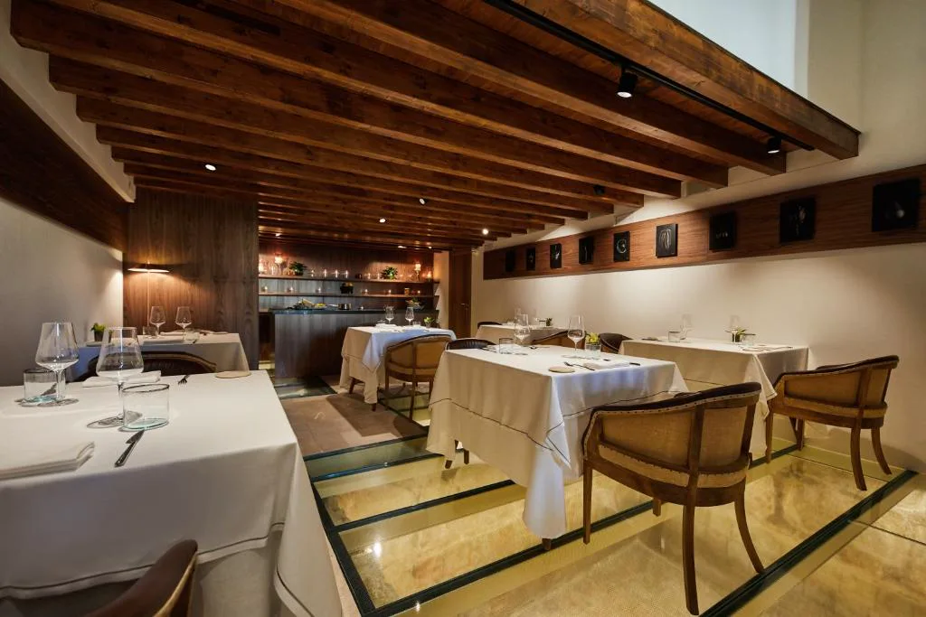 Restaurante interior con vigas de madera y mesas vestidas, Es Princep