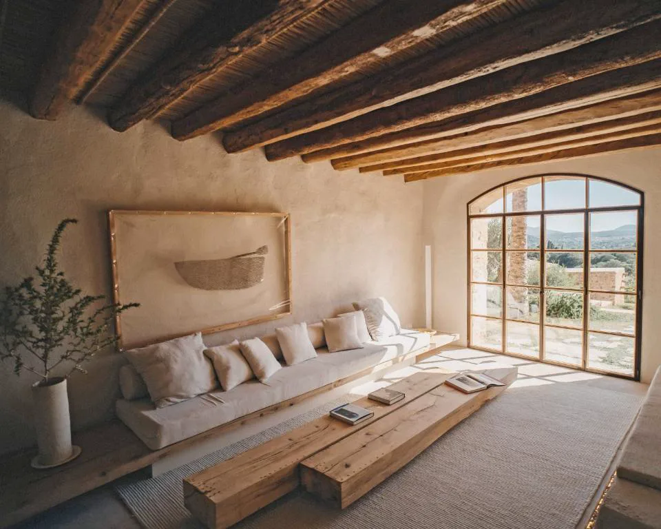 Salón con sofá de lino, chimenea de piedra y vistas al campo, Es Racó d'Artà