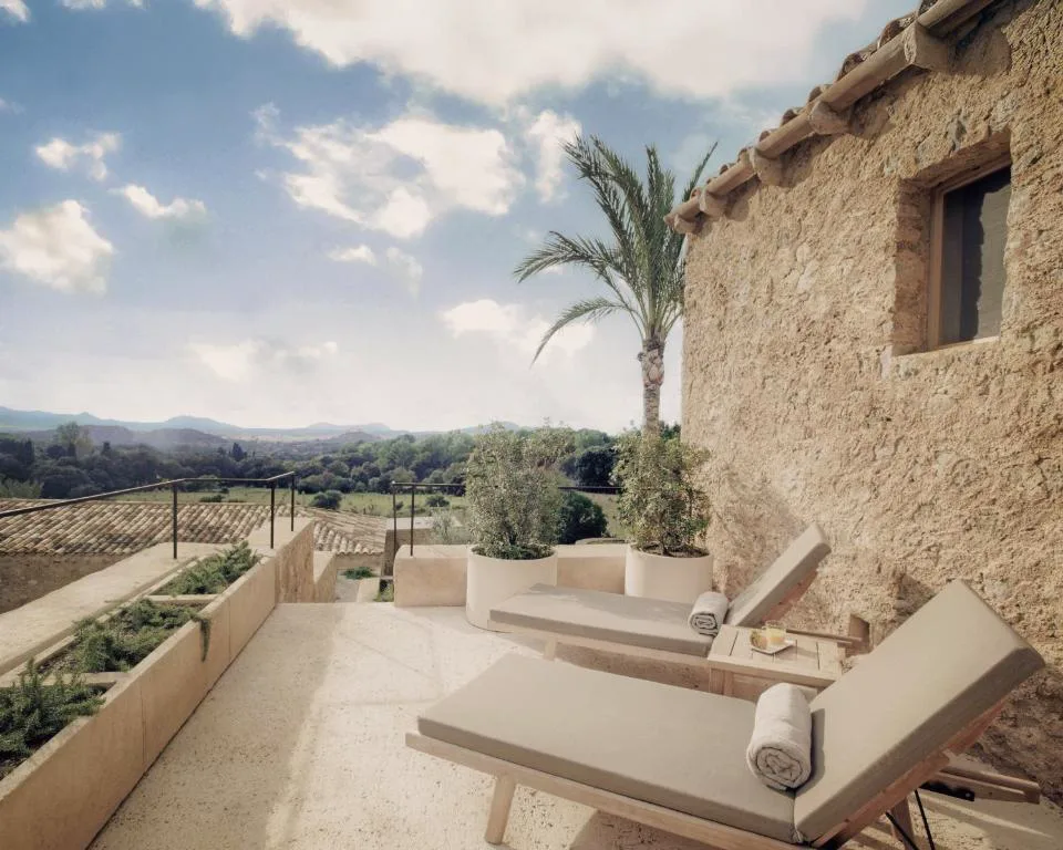 Terraza de piedra con tumbonas y palmera junto a las montañas de Artà, Es Racó d'Artà