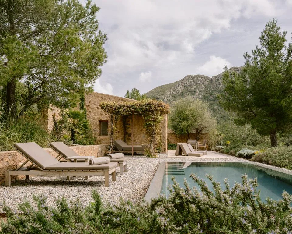 Piscina exterior entre pinos con las montañas de Artà al fondo, en la finca rehabilitada Es Racó d'Artà