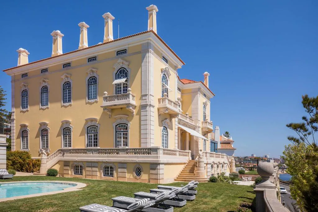 Fachada amarilla del palacio del Estoril Vintage Hotel con piscina y jardín frente al Atlántico