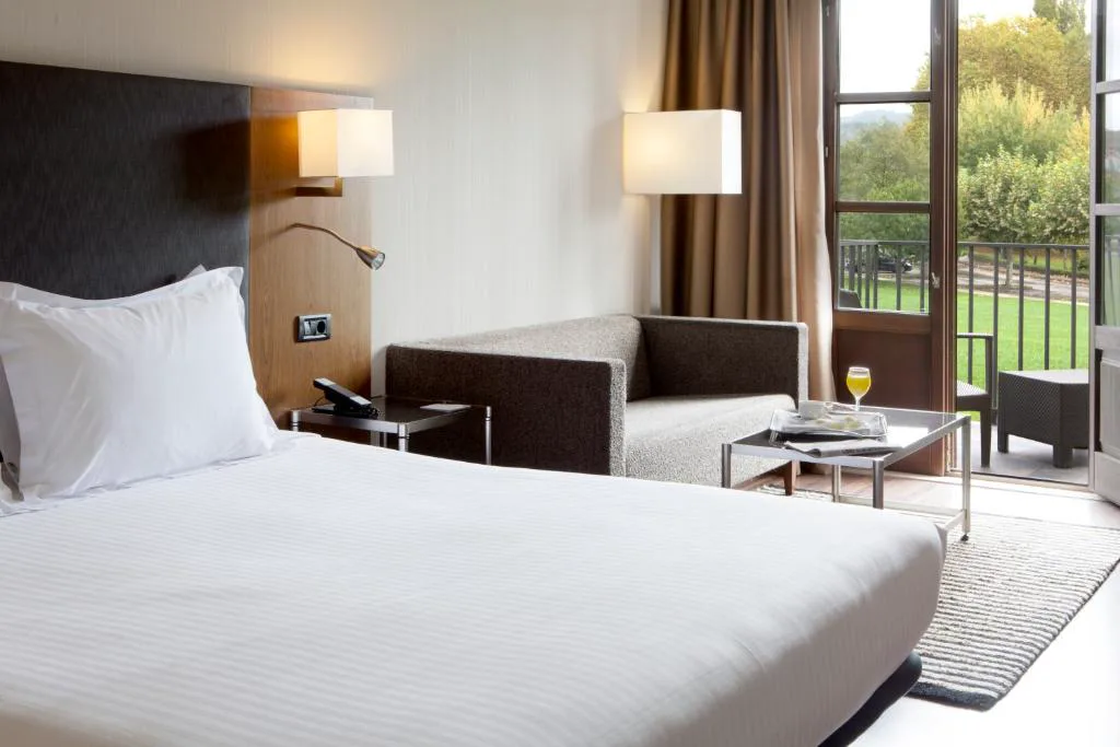 Dormitorio con sofá y terraza con vistas al jardín, Eurostars Vila de Allariz Hotel Balneario