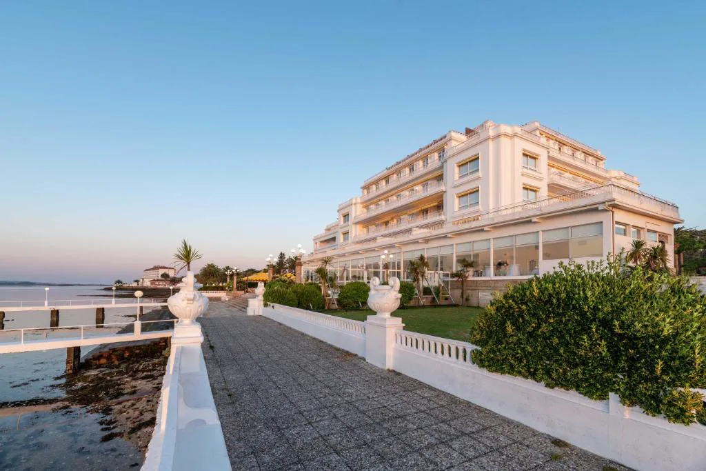 Paseo balaustrado junto a la ría con la fachada blanca del hotel al atardecer, Eurostars Gran Hotel La Toja