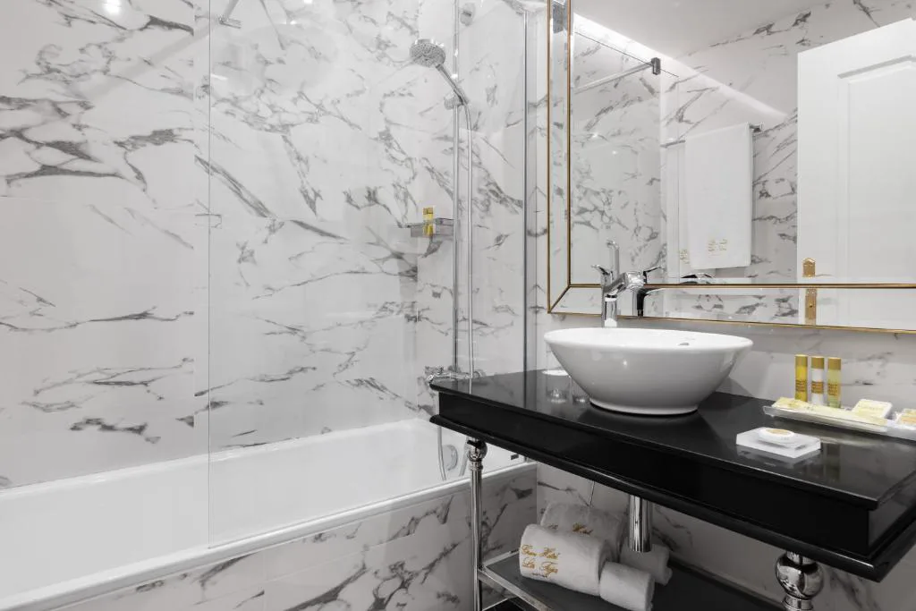 Baño de mármol con bañera, ducha y lavabo sobre encimera negra, Eurostars Gran Hotel La Toja