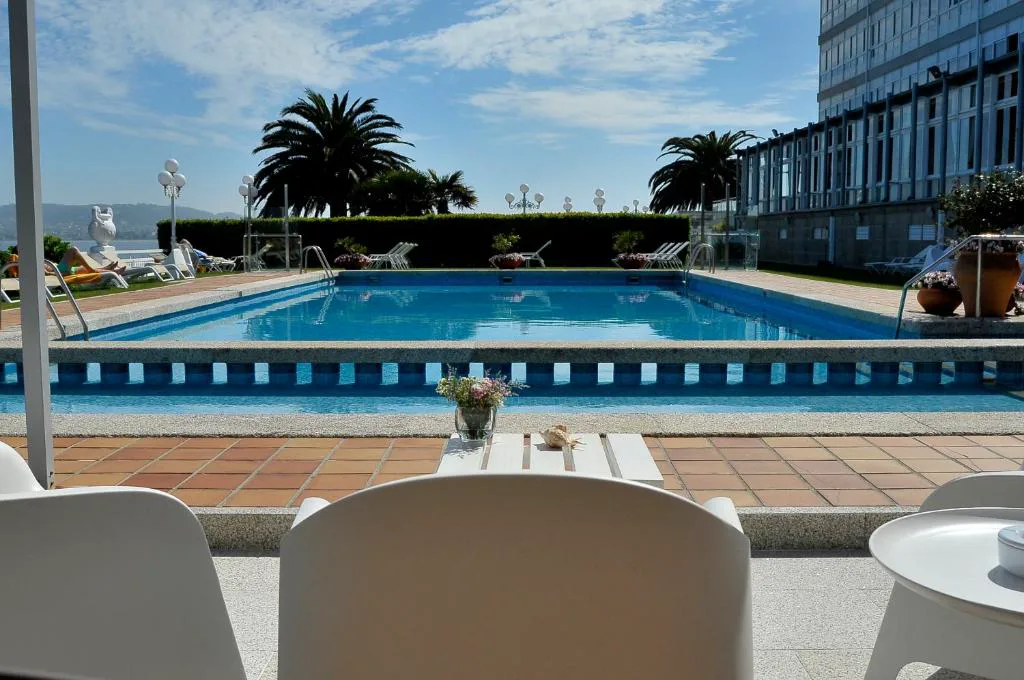 Piscina exterior con tumbonas y palmeras junto al edificio del hotel, Eurostars Louxo Talaso