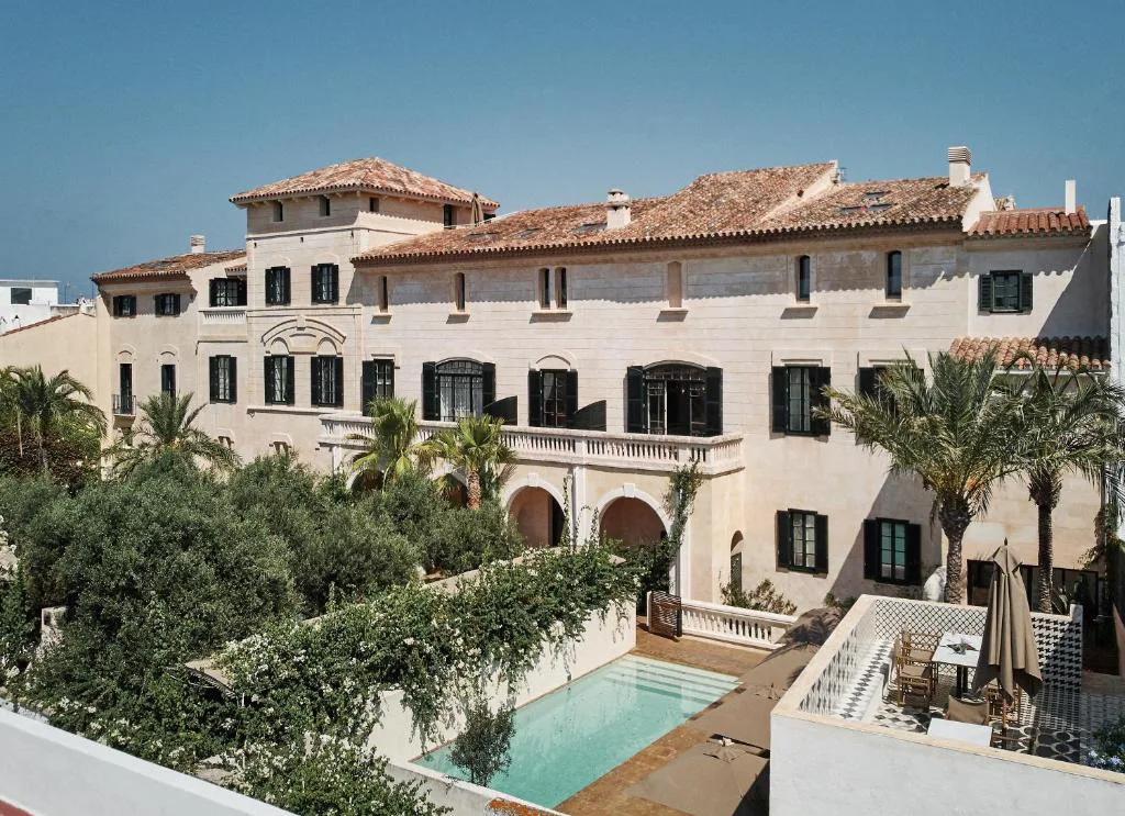Fachada palaciega de Faustino Gran Relais & Chateaux entre palmeras, en el centro de Ciutadella, Menorca