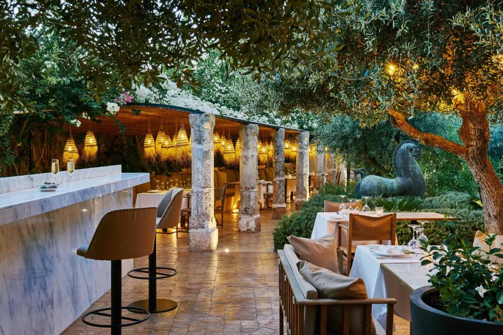 Jardín interior con mesas para cenar entre olivos iluminados, Faustino Gran Relais & Chateaux