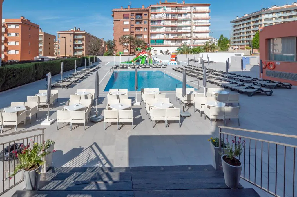 Piscina con tumbonas blancas junto al hotel