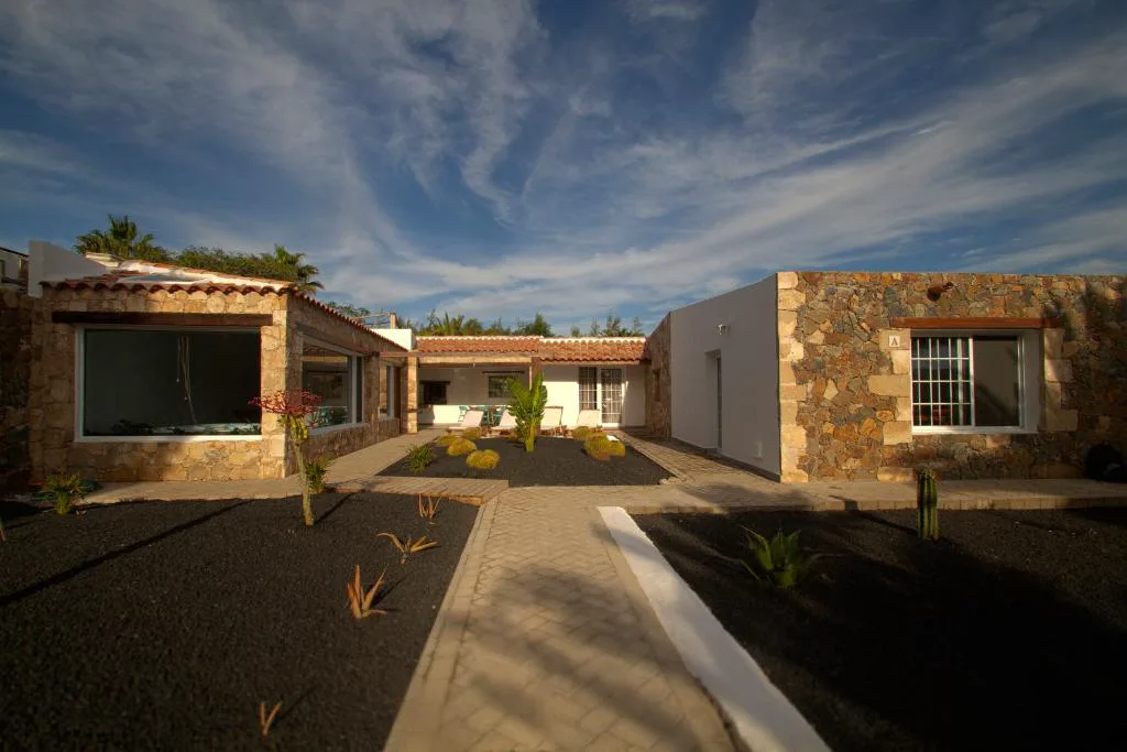 Fachada de piedra vista de la finca entre plantas de cactus y aloe vera, Finca Arbequina