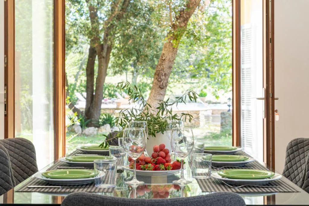 Mesa vestida con fruta fresca y copas de vino frente al jardín, Can Regalat