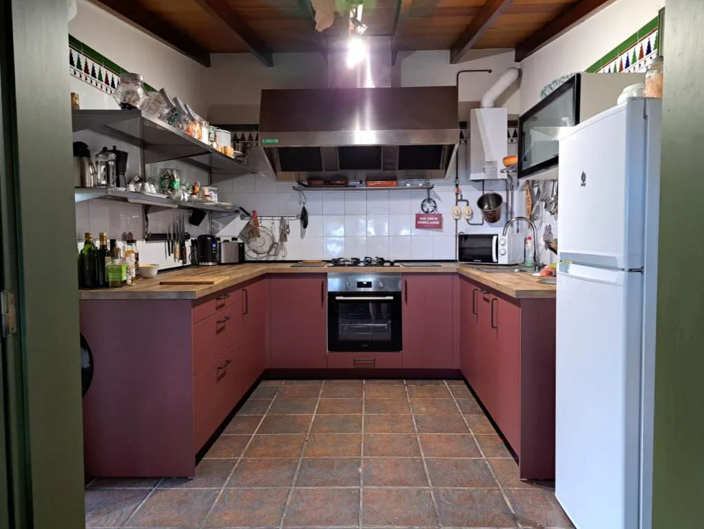 Cocina con muebles en tono granate y vigas de madera vista, Finca Cebollino