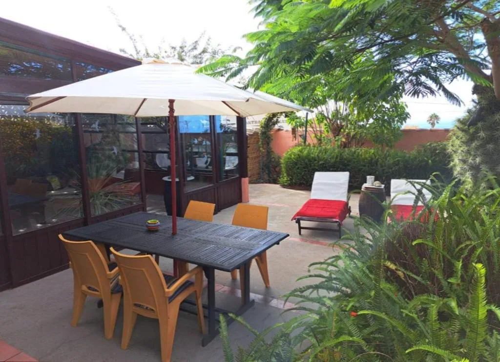 Terraza con sombrilla y tumbonas rojas rodeada de jardín, Finca Cebollino