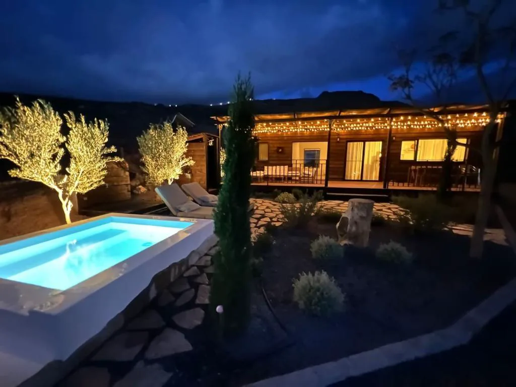 Piscina exterior con tumbonas de madera y pared de piedra volcánica, Finca Jardín del Norte