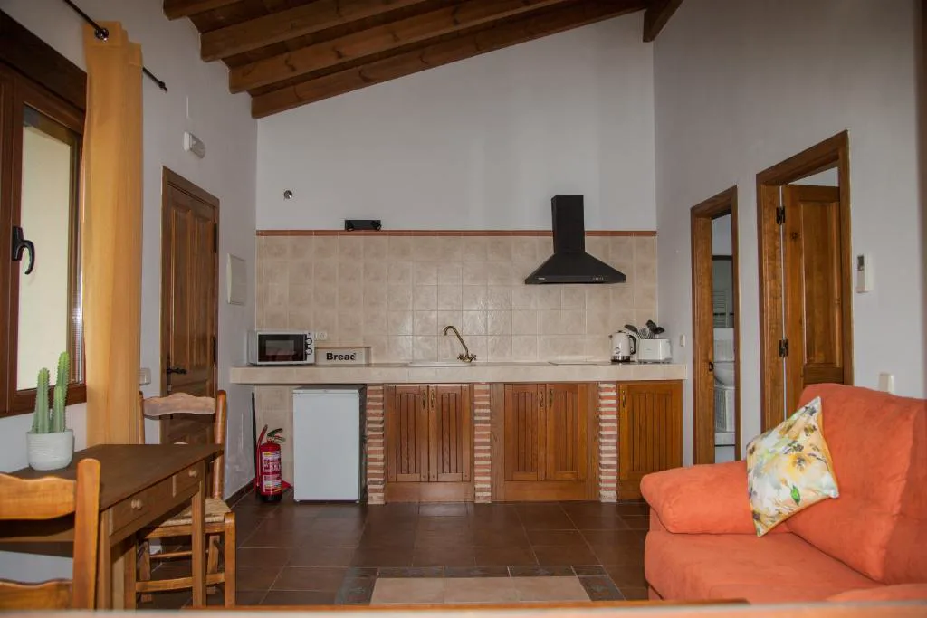 Cocina con puertas de madera y salón con vigas al fondo