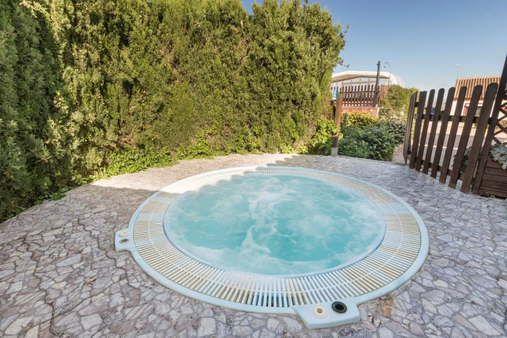 Jacuzzi redondo entre piedras y arbustos
