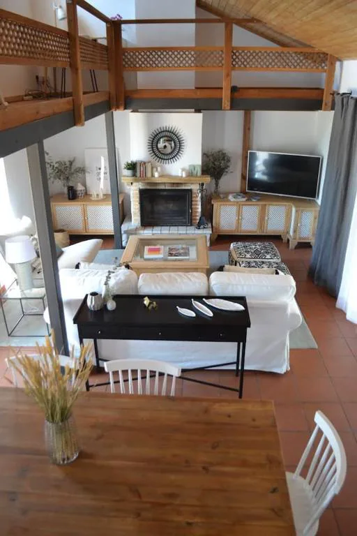 Salón con sofás y chimenea bajo una entreplanta