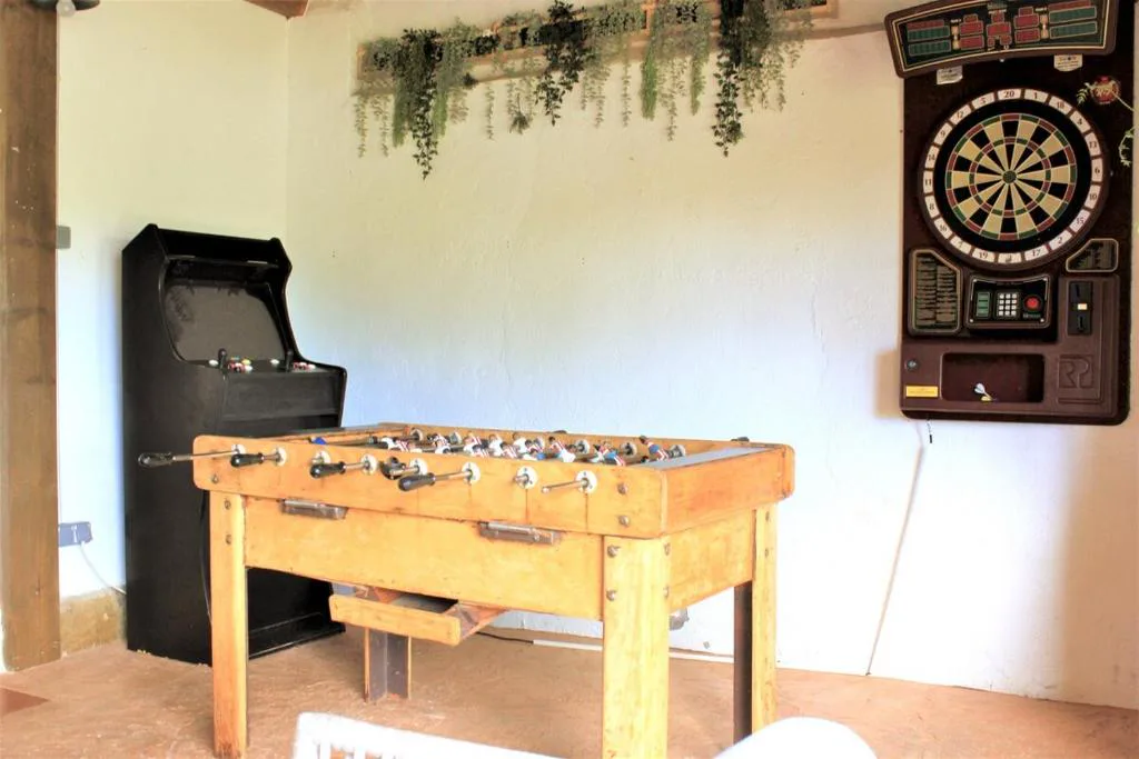 Sala de juegos con futbolín, diana y máquina recreativa