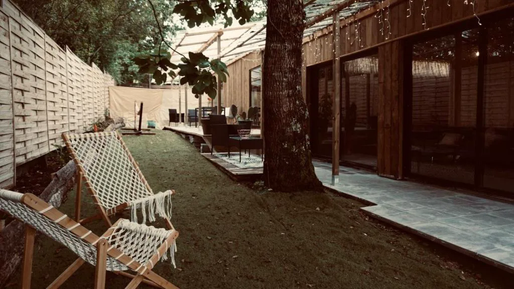 Fachada de madera con hamacas de macramé y puertas de cristal, Cabañas Finca Real