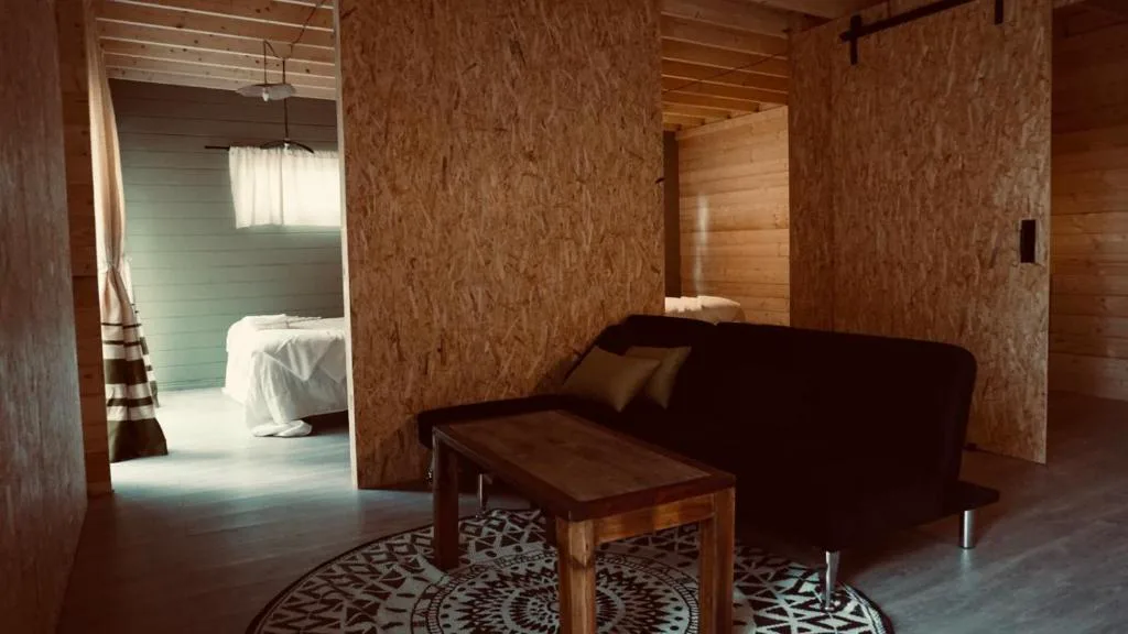 Salón con sofá y vistas al dormitorio a través de paredes de madera OSB