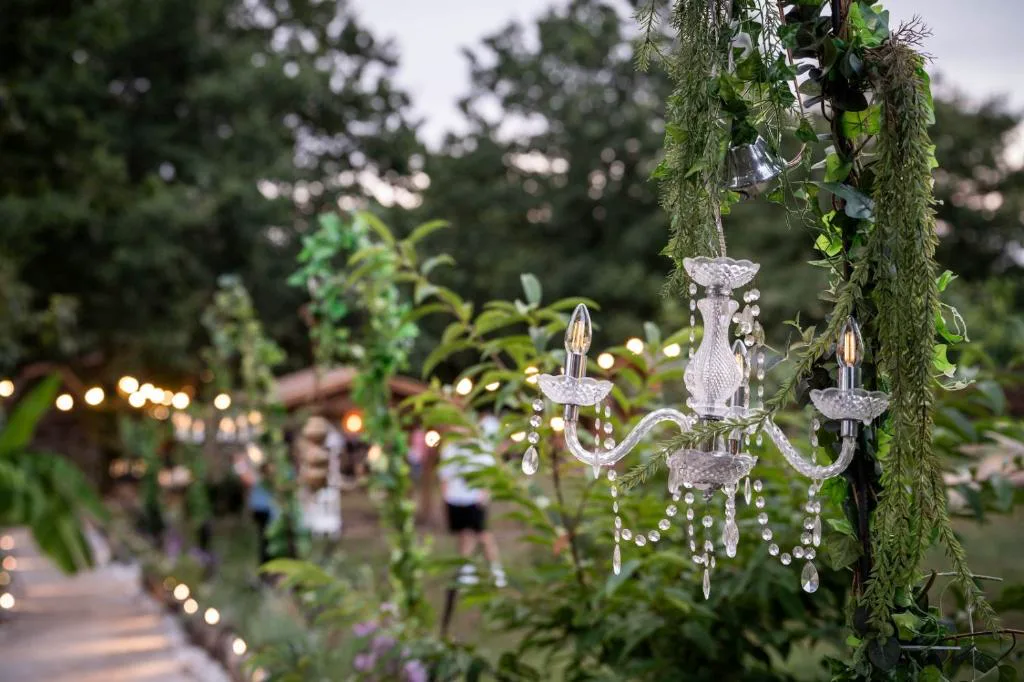 Jardín decorado con candelabro de cristal colgante entre plantas, Cabañas Finca Real