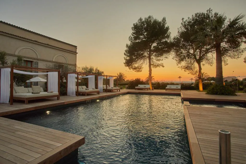 Piscina exterior al atardecer con camas balinesas de Fontsanta Hotel Thermal & Spa, en Colonia de Sant Jordi, Mallorca