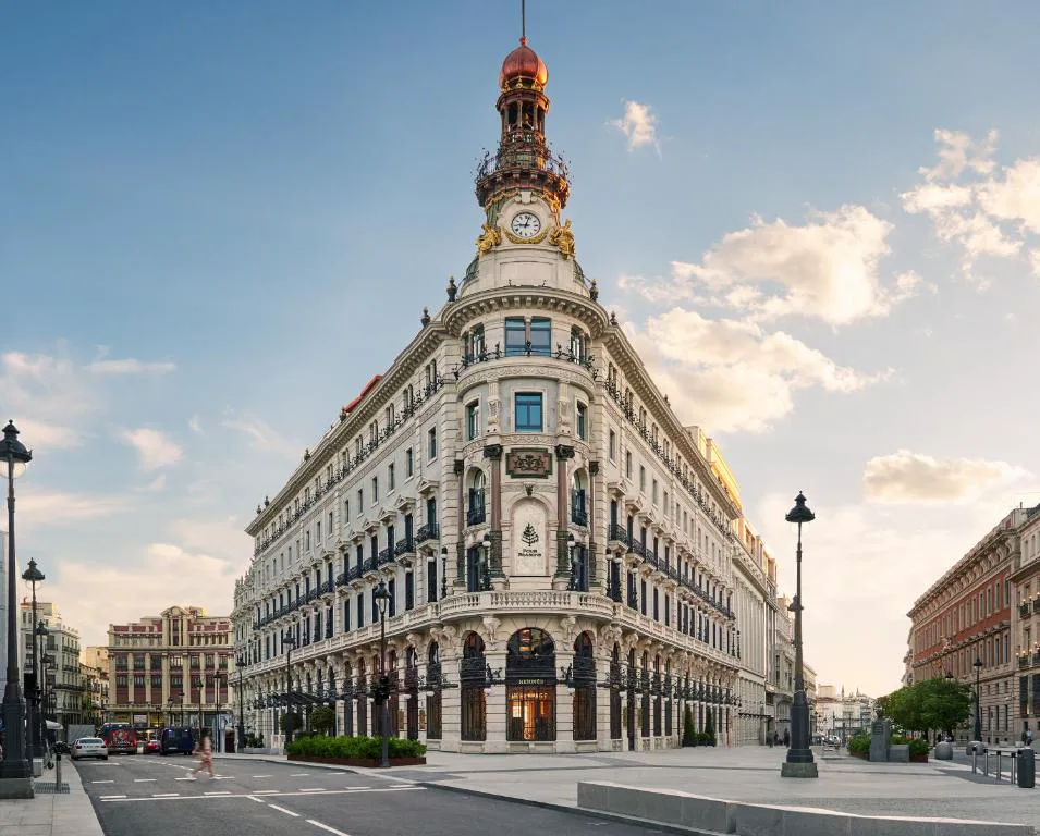 Fachada de un edificio histórico de esquina con torreón junto a una calle de Madrid